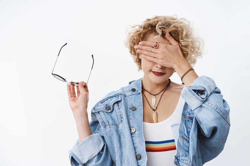 portrait-woman-cannot-look-gross-thing-taking-off-glasses-holding-frames-hand-as-covering-sight-with-palm-smiling-waiting-time-open-eyes-white-wall_176420-36020.jpg