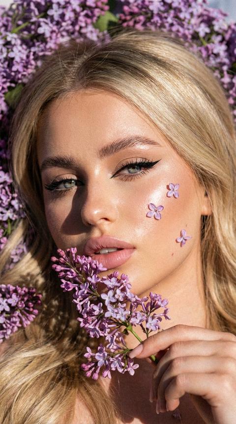 Кинематографический эффект с добавлением зерна Это экстремально близкий портрет женщины, фокусируется на её глазах и губах. Она смотрит прямо в камеру с уверенным взглядом. Её глаза выделяются благодаря смелому стрелковому макияжу, где линия тонкого чёрного лайнера плавно переходит в расширение, подчеркивая форму глаз. Ресницы густые, длинные, создающие эффект объема. Брови идеально оформлены с эффектом ламинирования. На губах матовый нежно розовый цвет. Свет солнечный падает с одной стороны, создавая мягкие тени, которые подчеркивают рельеф лица, особенно на щеках и линии подбородка. Освещение усиливает сияние на губах, что делает их более выразительными. Она лежит в цветах сирени, сирень частично попадает на лицо девушки, сирени вокруг очень много. Она рукой держит веточку сирени прислоняя к губам, губы слегка приоткрыты.
На лице частично цветочки от сирени
Кожа подсвечена хайлайтером
Волосы объемные длинные блестящие Кинематографический эффект с добавлением зерна Это экстремально близкий портрет женщины, фокусируется на её глазах и губах. Она смотрит прямо в камеру с уверенным взглядом. Её глаза выделяются благодаря смелому стрелковому макияжу, где линия тонкого чёрного лайнера плавно переходит в расширение, подчеркивая форму глаз. Ресницы густые, длинные, создающие эффект объема. Брови идеально оформлены с эффектом ламинирования. На губах матовый нежно розовый цвет. Свет солнечный падает с одной стороны, создавая мягкие тени, которые подчеркивают рельеф лица, особенно на щеках и линии подбородка. Освещение усиливает сияние на губах, что делает их более выразительными. Она лежит в цветах сирени, сирень частично попадает на лицо девушки, сирени вокруг очень много. Она рукой держит веточку сирени прислоняя к губам, губы слегка приоткрыты.
На лице частично цветочки от сирени
Кожа подсвечена хайлайтером
Волосы объемные длинные блестящие