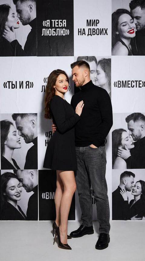 Создай изображение , 
Используй загруженные фотографии как ЕДИНСТВЕННЫЕ референсы лица и внешности персонажей. Строго сохранить идентичность, черты лица и
пропорции. Фотореалистичная студийная fashion-съёмка в полный рост. В кадре пара влюблённых - женщина и мужчина, стоят близко друг к другу. ощущение притяжения и близости.
Образы:
﻿﻿женщина - современный эффектный look: короткое платье, каблуки, акцент на красную помаду;
﻿﻿мужчина - чёрная водолазка, джинсы, минималистичный современный стиль.
Образы гармонируют, пара выглядит как fashion-пара.
Фон: чёрно-белые постеры ко Дню влюблённых с панелями одной и той же пары в разных состояниях: взгляд друг на друга, улыбка, близость, тихое счастье.
Графические элементы и надписи на русском:
«Я ТЕБЯ ЛЮБЛЮ», «МИР НА ДВОИХ», «ТЫ И Я», «ВМЕСТЕ».
Пара фотореалистичная, цветная, чётко отделена от иллюстрированного фона - эффект «живых людей внутри постера».
Мягкий студийный свет, естественная кожа, высокий фотореализм. Вертикальный формат, эстетика fashion + pop art + Valentine's editorial.
Без CGI, без мультяшности.