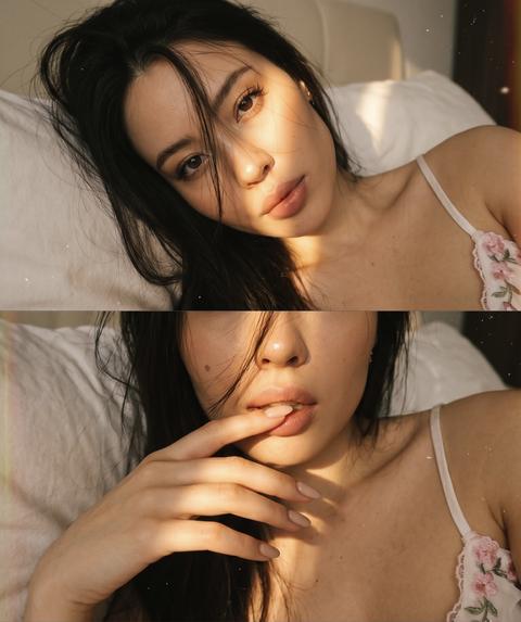 Сохранить внешность 1:1. Не изменять черты лица, пропорции. Композиция из триптиха. На ней девушка дома лежащей на кровати подушке в золотой час. На ней белый топ на тонких лямках с нежно розовыми вышитыми цветочками. Фото по пояс. На верхнем кадре портрет лица крупным планом, она смотрит в камеру полубоком, солнце полосой освещает лицо. Кадр по середине: близкий ракурс, девушка проводит рукой по губам. Нижний кадр: портрет крупным планом глаз, голова запрокинута назад. На всех кадрах её волосы падают на лицо закрывая часть. Цветовая палитра приглушена. Романтическое настроение. Присутствует видимая зернистость. На каждом кадре попадает солнечный свет, кинематографический эффект с добавлением зерна. Ногти нюдовые