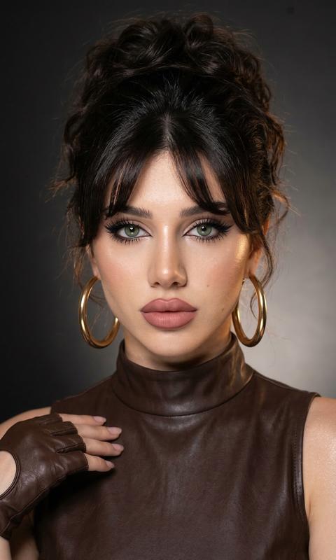 Не меняй лицо! Не меняй черты лица! Не меняй пропорции тела,! Волосы  собранные в высокий небрежный волнистый пучок в стиле 90-х челка шторка , 90s bombshell
messy updo, объем
у корней, curtain
bangs. Как съемка в 
90-х»
Размер 9:16 стиль vogue вспышка
Макияж с акцентом на глаза , глаза ярко выделены, стрелки cat нюдовые губы идеально очерчены карандашом на тон темнее помады пыльная Роза влажный хайлайтер на лице , густые черные ресницы с эффектом лучики .
Легкий шиммер по всему телу

Fujifilm GFX 100, 100mm lens, depth of field, subsurface scattering, soft morning light, Tyndall effect, hyper-detailed iris, unedited RAW photo 8k resolution
Тщательно обрамленный вертикальный портрет женщины, охватывающий её от верхней части груди до чуть выше головы, занимающий примерно 70% высоты кадра. Фон имеет гладкий, матовый градиент от темно-серого до черного, с теплой мягкой подсветкой сзади девушки более темный слева и переходящий в более мягкий серый справа, создавая тонкий эффект виньетирования. Лицо женщины смотрит прямо в анфас Мягкое, рассеянное ключевое освещение с 45 градусов слева и выше уровня глаз отбрасывает нежные тени на правой стороне её лица. волосы уложены в объемную прическу с мягкими прядями, обрамляющими лицо. Она носит безрукавный высокошейный темно-коричневый кожаный наряд с коричневой кожаной перчаткой без пальцев на левой руке. Макияж включает градиентный теней, подводку и помаду цвета маув-браун. Перспектива камеры на уровне глаз с узкой глубиной резкости. Изображение имеет высокую четкость, теплые тона кожи и легкий размытый фон. В ушах массивные золотые круглые серьги .