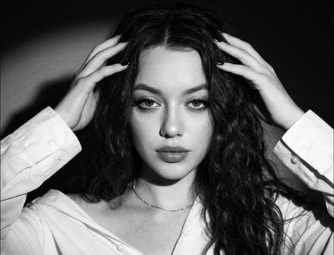 Создай коллаж из 2х фотографий, не меняя черты лица. Черно-белый художественный портрет молодой женщины в стиле нуар. Крупный план, чувственная и загадочная атмосфера. Девушка с объемными темными волосами и выразительными губами обнимает себя за плечи. Безупречный макияж, длинные волосы. На ней белая рубашка , которая спущена с плеч, на шее тонкая короткая изящная цепочка. Драматичное контрастное освещение (киароскуро), создающее глубокие тени: лицо и одно плечо ярко освещены направленным светом, остальное погружено во тьму. На заднем фоне мягкое световое пятно (ореол). На стене ее тень. Текстура кожи реалистичная, видна легкая зернистость кинопленки 35 мм. Высокая детализация, эстетика старого Голливуда, минимализм.
на нижнем фото девушка смотрит четко в камеру, руками касается волос. На двух кадрах одна и та же девушка, в одинаковом образе. Ногти квадратные черные. 