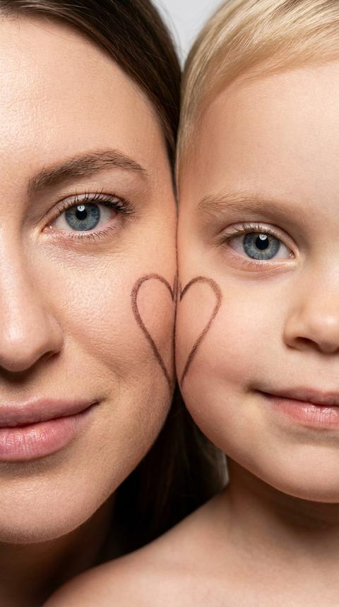 Ультрареалистичный студийный макропортрет. Формат 9:16; Не меняй черты лица.
На фотографии два человека — мама и ребёнок, щёка к щеке, в кадре видна только половина лица каждого . Одежду не видно. Оба смотрят прямо в камеру с мягкой улыбкой. На щеке мамы изображена половина сердечка, на щеке ребёнка — вторая половина, вместе они образуют одно цельное сердце. Снимок сделан профессиональной камерой (85 мм f/2.0, ISO 200, 1/160 с). Яркий фронтальный свет создаёт чёткие тени и чистые блики. Чистый студийный фон, малая глубина резкости, высокая детализация кожи, красивая гладкая кожа.