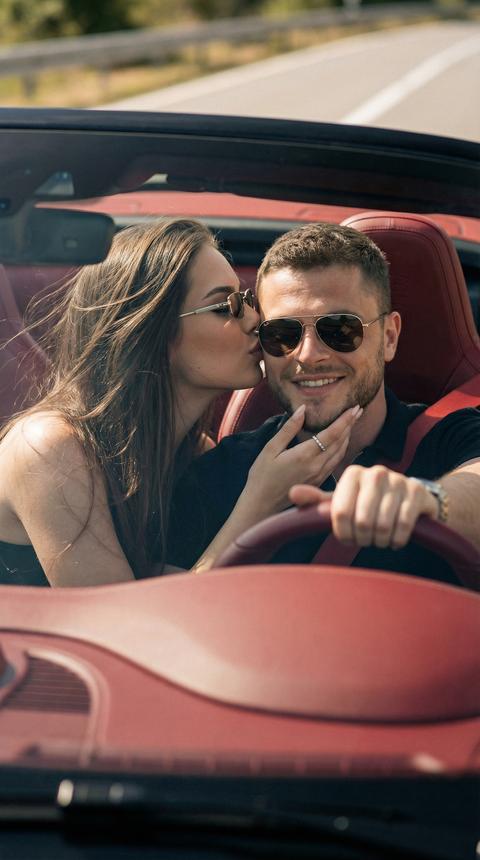 Ультрареалистичная кинематографичная фотография, созданная на основе фото-референса с сохранением идентичности лиц и естественных пропорций без стилизации и искажений.
Женщина нежно целует мужчину в висок, сидя рядом с ним в кабриолете Porsche 911 с полностью открытой крышей.
Мужчина находится за рулём, корпус направлен вперёд, одна рука лежит на руле. Он с естественной улыбкой. На нём стильные брендовые очки-авиаторы с тонкой металлической оправой и слегка затемнёнными линзами, подчёркивающие расслабленный премиальный стиль путешествия.
Женщина наклоняется к нему со стороны пассажирского сиденья, мягко целуя его в висок. Одной рукой она нежно касается его подбородка и щеки. Выражение лица спокойное, чувственное и естественное, без постановочности.
У женщины волосы слегка развеваемые ветром, они свободно падают на плечи. Макияж мягкий, естественный, подчёркивающий свежесть кожи: лёгкий бронзер, натуральные губы, аккуратные ресницы. Она также носит брендовые узкие солнцезащитные очки, современные с тёмными линзами и тонкой премиальной оправой, создающие эффект дорогого road-trip образа.
Салон автомобиля выполнен в насыщенной красной кожаной отделке, хорошо видны сиденья, подголовники и детали дверей, создающие контраст с дневным светом.
Сцена снята под углом примерно 45 градусов спереди, камера расположена немного выше уровня глаз, создавая ощущение присутствия внутри машины.
Солнечный день, тёплый естественный свет мягко подсвечивает кожу и детали салона. Ветер слегка колышет волосы, создавая ощущение движения. Фон дороги слегка размыт, создавая глубину и ощущение спонтанного путешествия.
Атмосфера кадра романтичная, расслабленная, живая — момент, пойманный во время поездки, без постановочной глянцевости.
Изображение выглядит как дорогая рекламная или fashion-travel съёмка: высокая детализация кожи, реалистичные текстуры, мягкая глубина резкости, натуральные цвета, без CGI и без излишней ретуши.
Параметры съёмки:
Camera: Canon EOS R5
Lens: 85mm
Aperture: f/1.4
ISO: 100
Shutter Speed: 1/1000s
Natural daylight
Shallow depth of field
Aspect ratio: 9:16
Ultra-realistic, cinematic color grading, 8K detail.
Не меняй черты лица 