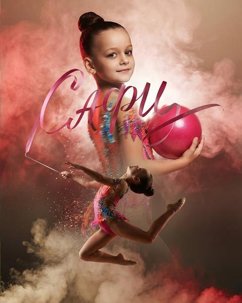 Cinematic sports poster of a rhythmic gymnast, double exposure composition inspired by the provided image.
Background (Portrait): A large portrait of the gymnast from the chest up, looking at the camera with a soft, confident smile. The hair is styled in a neat professional bun. The gymnast is holding a large pink gymnastic ball. The lighting is dramatic and warm with a soft glow.
Foreground (Action): A full-body shot of the same gymnast in a dynamic "grand jeté" jump or split leap in mid-air. The athlete is wearing a highly detailed, colorful rhythmic gymnastics leotard decorated with crystals, sequins, and fringes that seem to shimmer.
Artistic Elements: A flowing pink gymnastic ribbon swirls around the gymnast, artistically forming the shape of the name "{FULLNAME}" in elegant, fluid calligraphy across the center of the image. A decorative team monogram/logo in the lower right corner, rendered with a shimmering, elegant embossed effect.
Atmosphere: Dense clouds of colored cinematic smoke and dust (pink, red, and white) surround the athlete, creating a dreamlike, powerful atmosphere. Shimmering particles, sparkles, and magic dust are flying around the action pose.
Technical Specs: Photorealistic, ultra-detailed skin and fabric textures, 85mm lens, f1.8, high contrast, dramatic studio lighting, professional sports advertisement, poster layout, 4k, high detail, sharp focus on the face and the jumping figure.
Color Palette: Warm golden highlights, deep moody shadows, vibrant pinks and reds from the smoke and ribbon