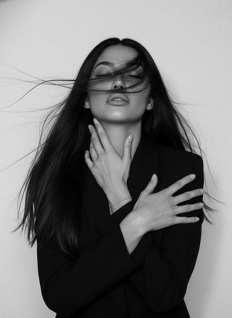 Reference image: conceptual variant.
Black and white artistic portrait, medium-close framing. Девушка занимает центр кадра, корпус слегка развернут, плечи видны. Голова наклонена назад и немного в сторону, подбородок вытянут, глаза закрыты, выражение лица спокойное и глубокое, с намёком на внутреннее напряжение. Hair: long, loose, wind-swept strands crossing the face and cheekbones, несколько прядей плавно тянутся по воздуху. Pose: обе руки подняты к шее и ключицам. Одна рука касается шеи, пальцы вытянуты, вены и анатомия видны. Вторая рука пересекает грудь, ладонь лежит на плече, пальцы длинные, естественные, ногти короткие без акцента. Запястье с тонкой едва заметной нитевой резинкой. Outfit: structured black blazer with sharp minimal silhouette, без видимых деталей, ткань matte, контрастная к коже. Фигура читается через форму и негативное пространство. Lighting: high-contrast soft directional light, smooth gradients, sculpted cheekbones, deep shadows under jawline. Background: clean white, seamless, no texture. Camera: medium close-up, straight-on angle, shallow depth of field, crisp detail on face and hands, slight grain for analog feel. Mood: raw elegance, introspection, tension, wind-driven stillness, fashion editorial minimalism. Reference image: conceptual variant.
Black and white artistic portrait, medium-close framing. Девушка занимает центр кадра, корпус слегка развернут, плечи видны. Голова наклонена назад и немного в сторону, подбородок вытянут, глаза закрыты, выражение лица спокойное и глубокое, с намёком на внутреннее напряжение. Hair: long, loose, wind-swept strands crossing the face and cheekbones, несколько прядей плавно тянутся по воздуху. Pose: обе руки подняты к шее и ключицам. Одна рука касается шеи, пальцы вытянуты, вены и анатомия видны. Вторая рука пересекает грудь, ладонь лежит на плече, пальцы длинные, естественные, ногти короткие без акцента. Запястье с тонкой едва заметной нитевой резинкой. Outfit: structured black blazer with sharp minimal silhouette, без видимых деталей, ткань matte, контрастная к коже. Фигура читается через форму и негативное пространство. Lighting: high-contrast soft directional light, smooth gradients, sculpted cheekbones, deep shadows under jawline. Background: clean white, seamless, no texture. Camera: medium close-up, straight-on angle, shallow depth of field, crisp detail on face and hands, slight grain for analog feel. Mood: raw elegance, introspection, tension, wind-driven stillness, fashion editorial minimalism.