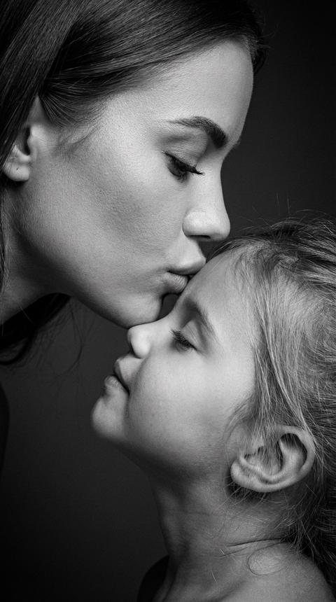 Фотореалистичный чёрно-белый портрет по загруженным фото.
СТРОГО сохранить внешность мамы и ребёнка 1:1: черты лица, пропорции, возраст, текстуру кожи.
Исходные фото - эталон лиц.
Композиция: экстремально крупный план, в кадре только лица. Профиль, диагональ: мама слева и выше, ребенок справа ниже. Мама наклоняется и целует ребенка в лоб; ребёнок тянется к маме вверх, глаза закрыты.
Минимализм. тёмный градиент.
Свет: контрастный студийный ч/б, мягкий ключ + заполняющий, высокий микроконтраст, глубокие тени, чистые полутона.
Обработка: highend ч/б, лёгкая локальная резкость, мягкий cinematic grain, лёгкое затемнение краёв.
Без пластики - поры и текстура сохранены.
Атмосфера тихая, нежная, интимная.
Максимальный фотореализм