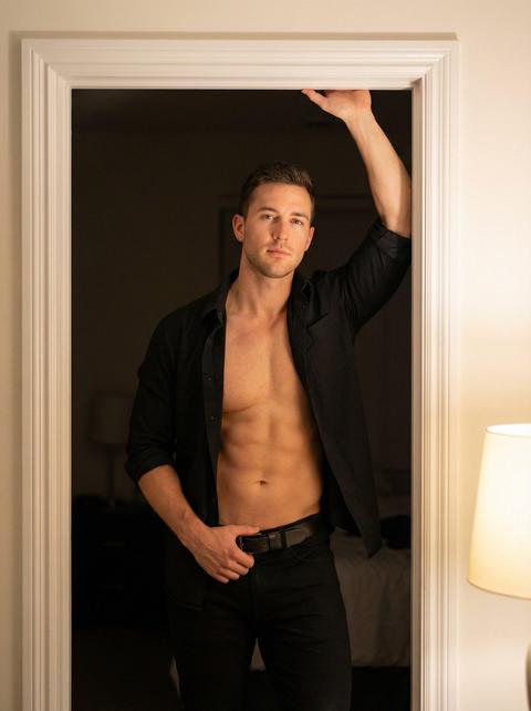 Фотореалистичный портрет мужчины, стоящего в дверном проеме, поясной план на уровне глаз, одна рука поднята и держится за притолоку, другая рука касается его ремня. У мужчины мускулистая, рельефная грудь и пресс. На нем черная расстегнутая рубашка с закатанными рукавами и черные брюки с черным ремнем. Действие происходит в интерьере с белой дверью и мягким, теплым искусственным освещением в комнате. Свет направлен спереди и немного сбоку, контраст умеренный, за дверным проемом видна темная комната. Снято на портретный объектив 85 мм, фотореалистично.