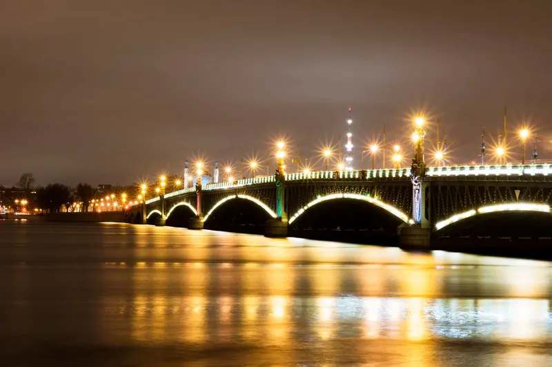 Ночная подсветка и арки Троицкого моста с отражением в воде