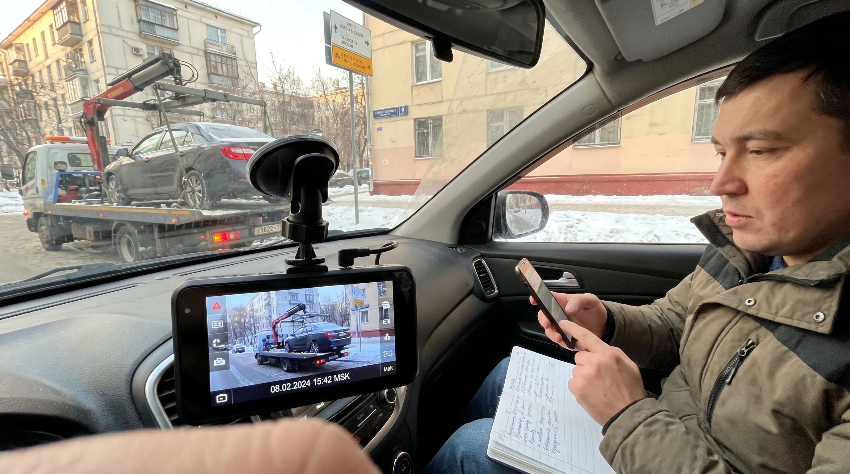 Эвакуатор грузит легковой автомобиль во дворе