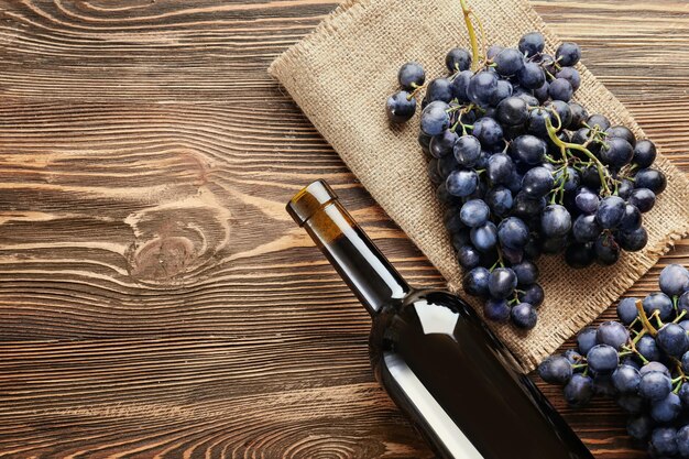 fresh-ripe-grapes-and-bottle-of-wine-on-wooden-background_392895-550146